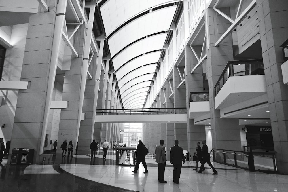 people walking inside building in grayscale photography