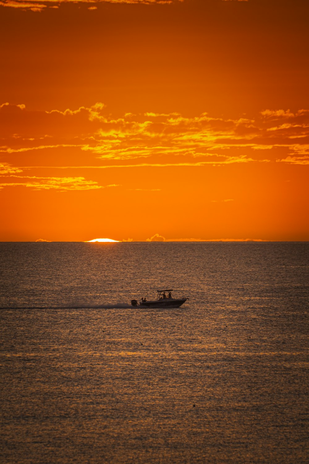 silhouette of boat on sea during sunset