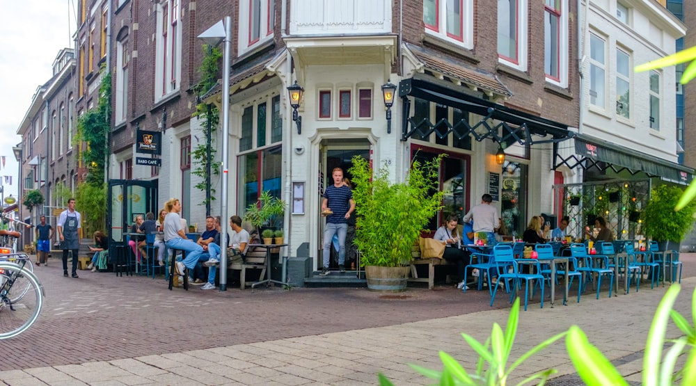 people sitting on blue chairs outside restaurant during daytime