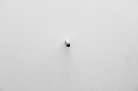 A small object next to a large one on a minimalist surface.
