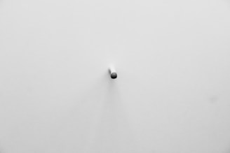 A small object next to a large one on a minimalist surface.