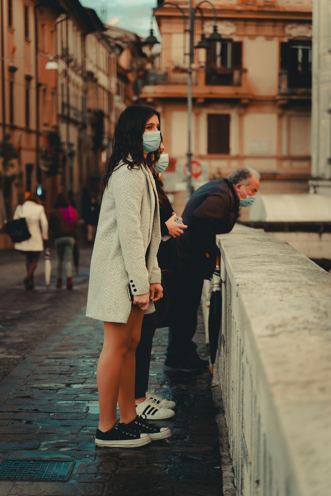 woman in black coat and white skirt walking on sidewalk during daytime