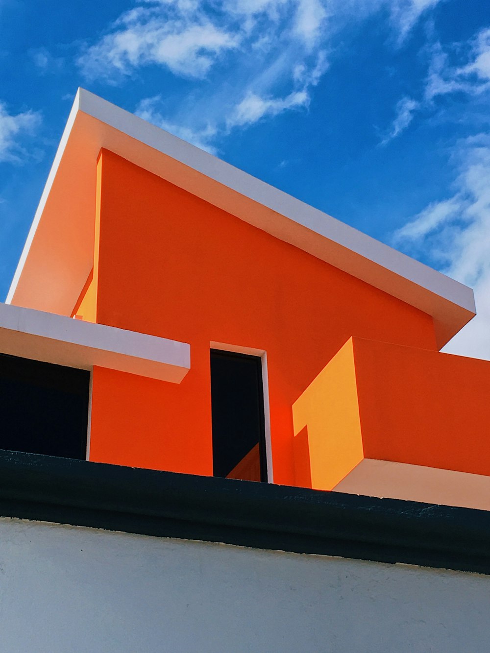 昼間の青空にオレンジと白のコンクリートの建物