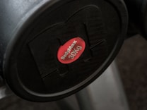 A black weight plate with a red center label displaying the brand name 'BodyMax' and the weight '30kg'. The weight appears attached to a piece of gym equipment.