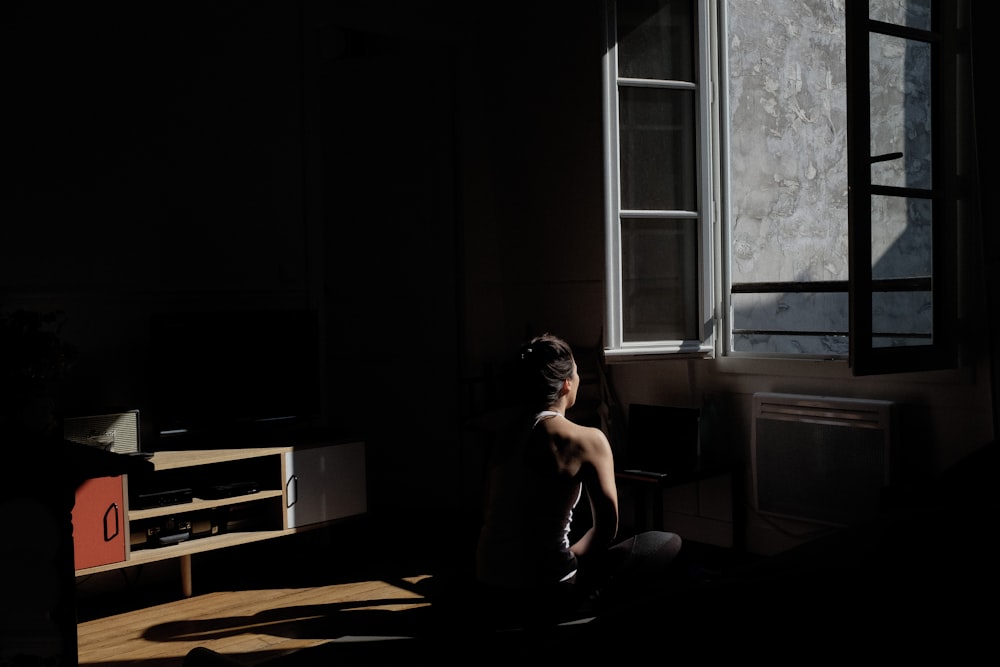 topless man sitting on floor near window