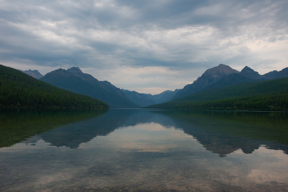 green mountains beside lake under cloudy sky during daytime