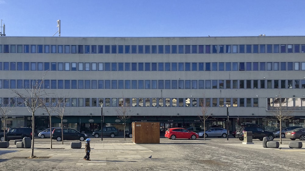 Coche rojo aparcado cerca de un edificio de hormigón blanco durante el día