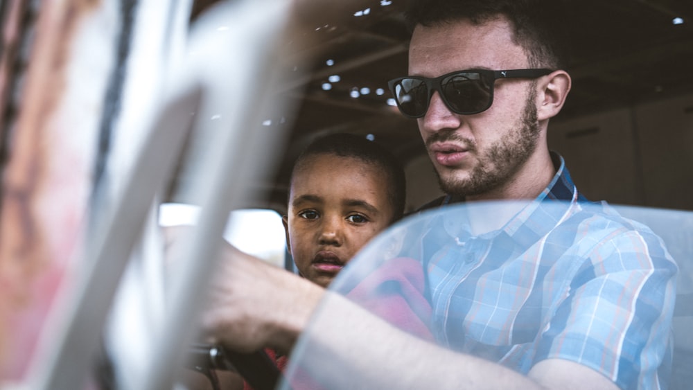 man in blue and white plaid shirt wearing black sunglasses