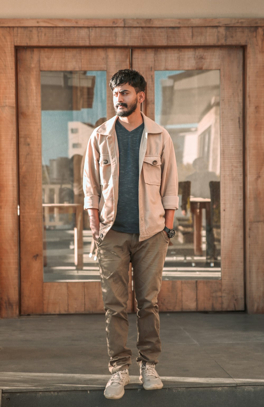 man in white dress shirt and blue denim jeans standing beside brown wooden wall during daytime