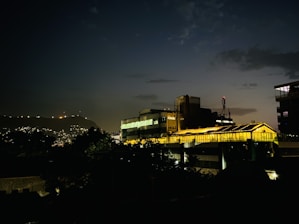 Evening cityscape of Birmingham B6 featuring industrial-style buildings highlighted by warm golden lights.