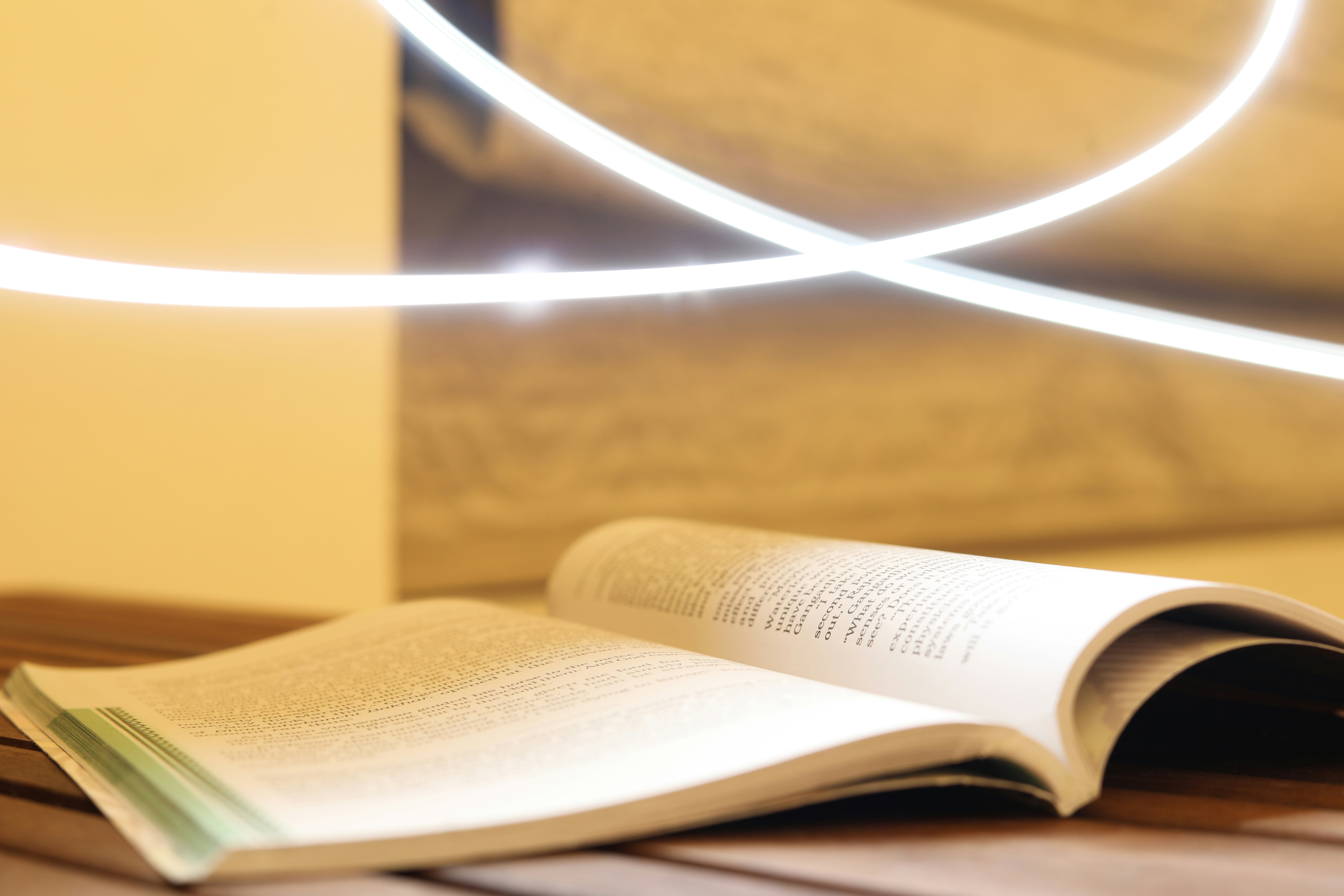 Open book on wooden table bathed in warm natural window light, peaceful and contemplative atmosphere