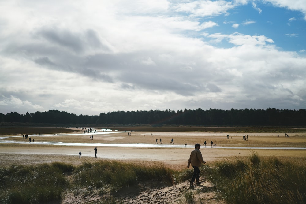 man in black shirt walking on brown field during daytime