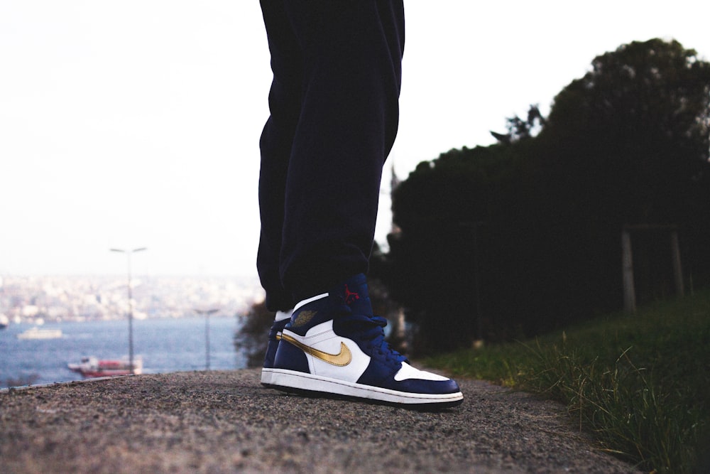 person in black pants and blue and white nike sneakers