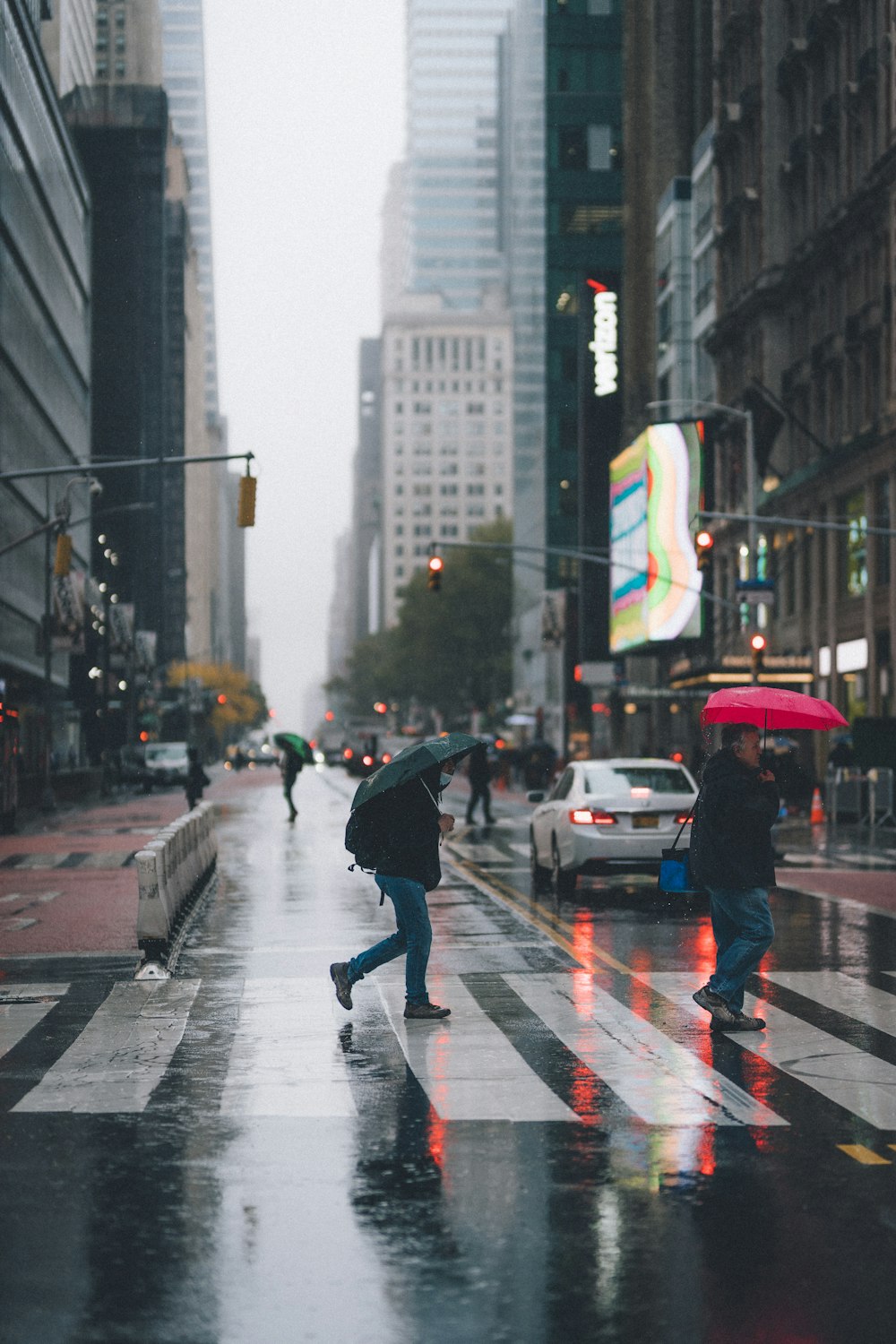 man in black jacket and pants walking on pedestrian lane during daytime