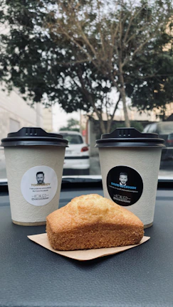 Close-up of a chic glasses case resting on a car dashboard next to a steaming coffee cup.
