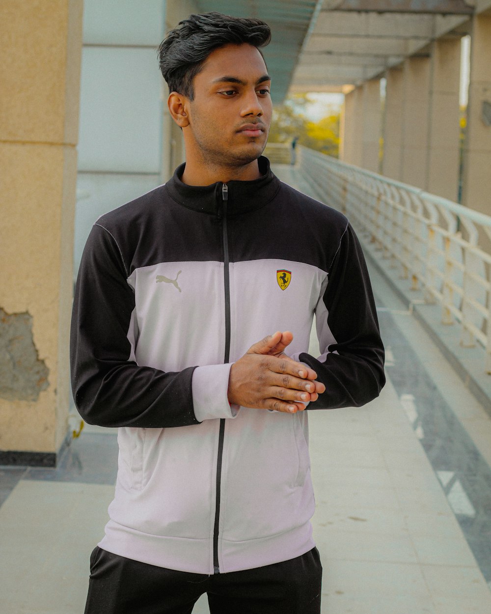 man in black and white zip up jacket standing on sidewalk during daytime