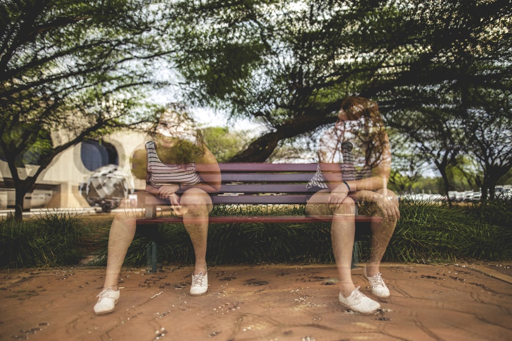 man and woman sitting on brown wooden bench during daytime