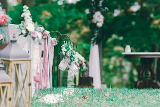 A sunlit tropical garden setting decorated for a wedding ceremony with colorful blooms and hanging lanterns.