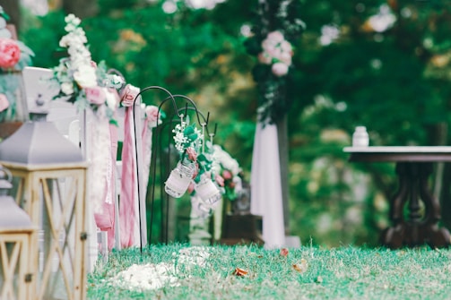 A sunlit tropical garden setting decorated for a wedding ceremony with colorful blooms and hanging lanterns.