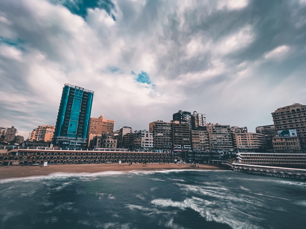 city skyline near body of water under cloudy sky during daytime