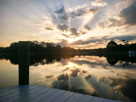 Sunset over a calm southern lake with a wooden dock and a small fishing boat.