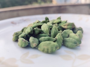 Close-up of vibrant cardamom pods spilling from a rustic burlap sack onto a wooden table.