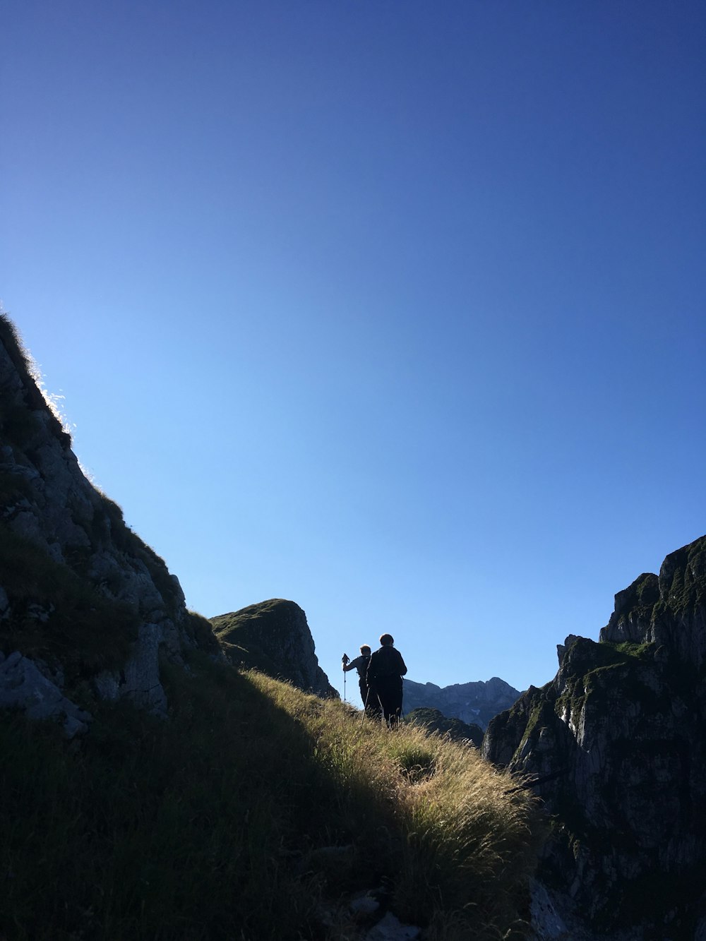 person standing on green grass field near rocky mountain during daytime