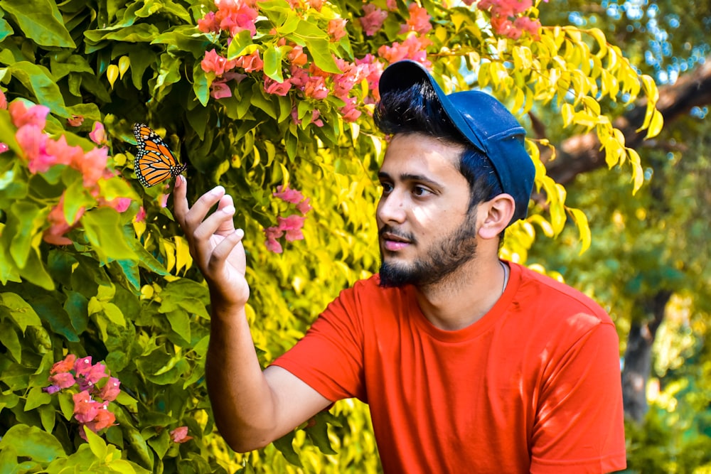 man in red crew neck t-shirt holding yellow and red flower