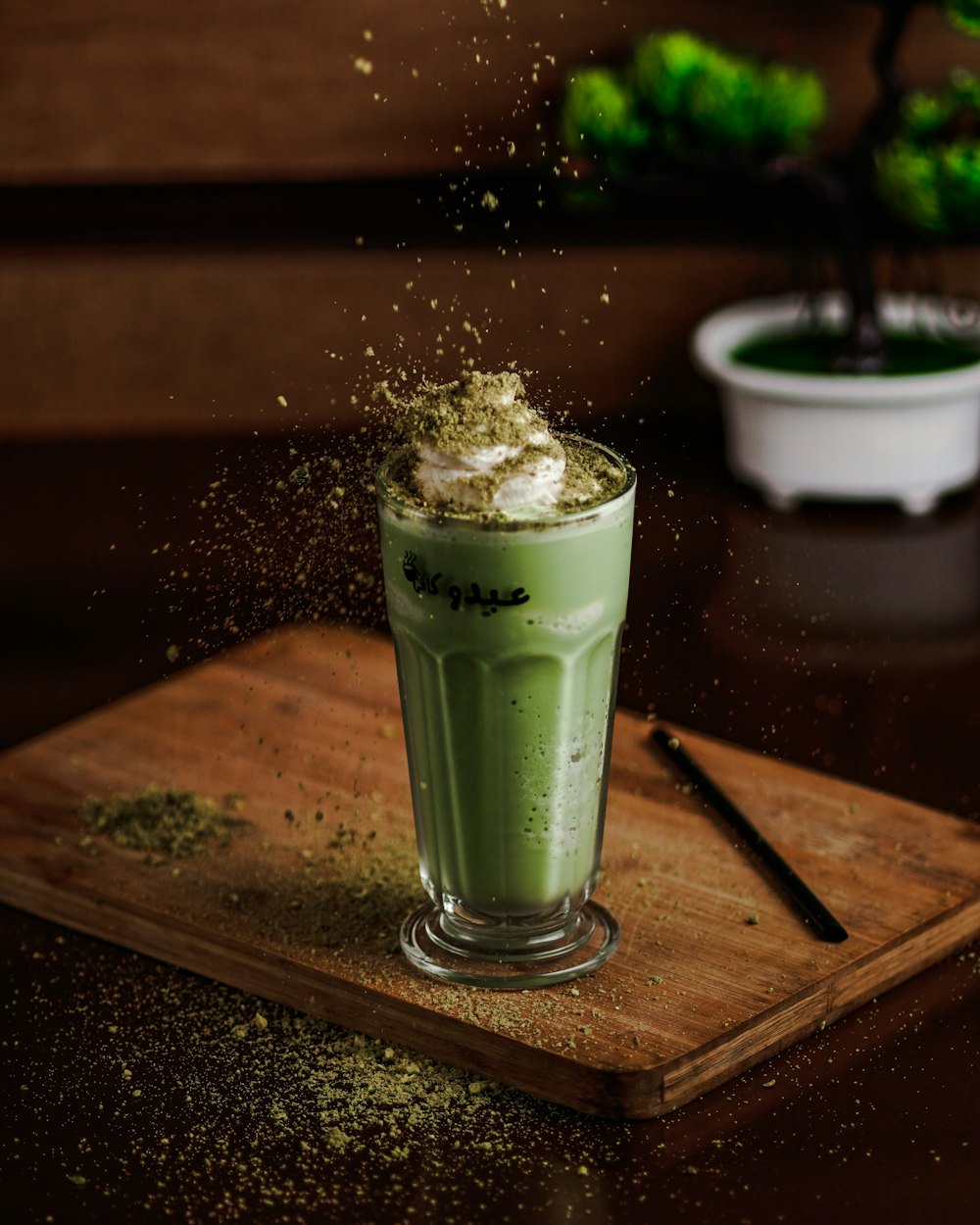 clear drinking glass with green liquid on brown wooden table