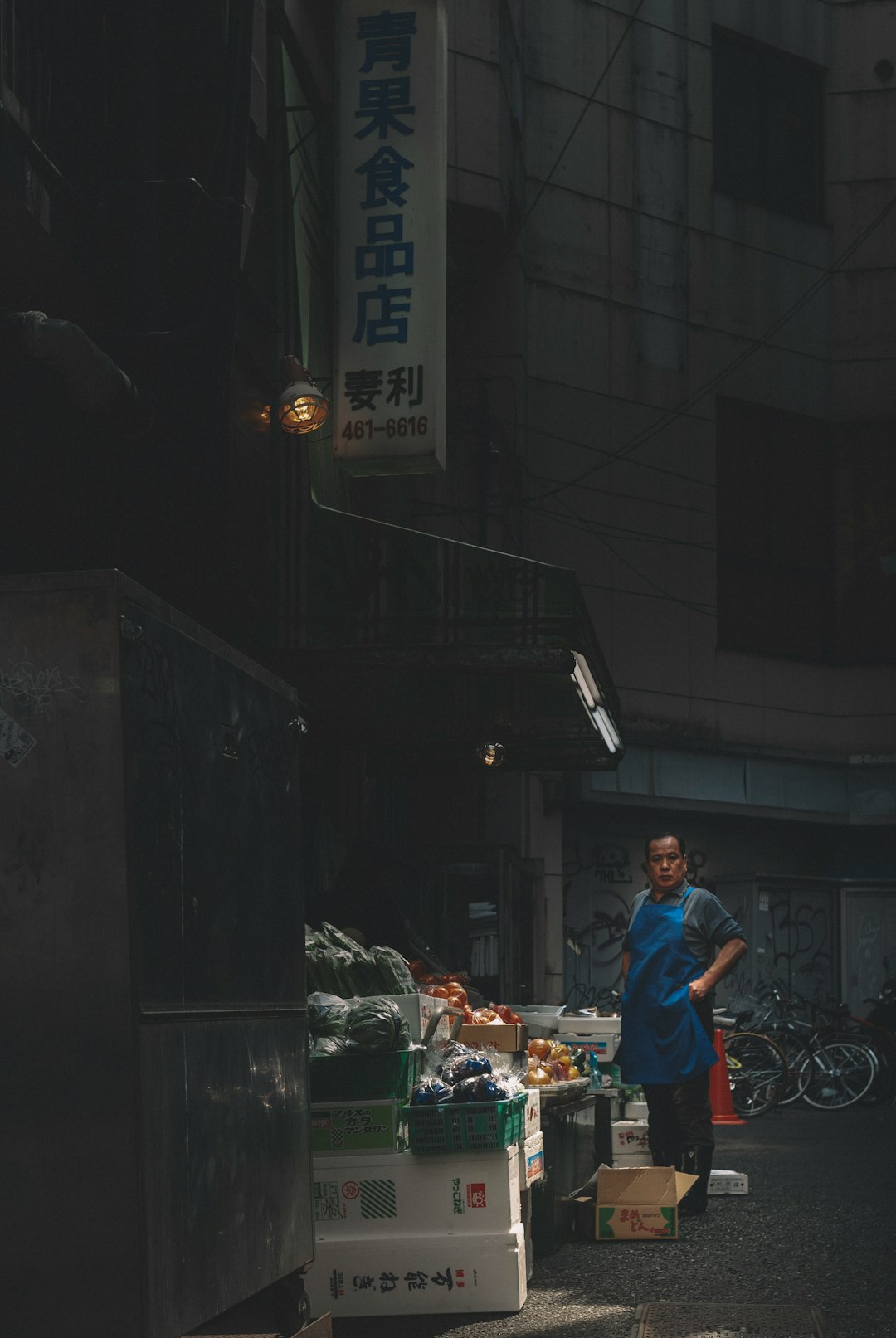 man in red t-shirt and blue denim jeans standing near food stall during nighttime