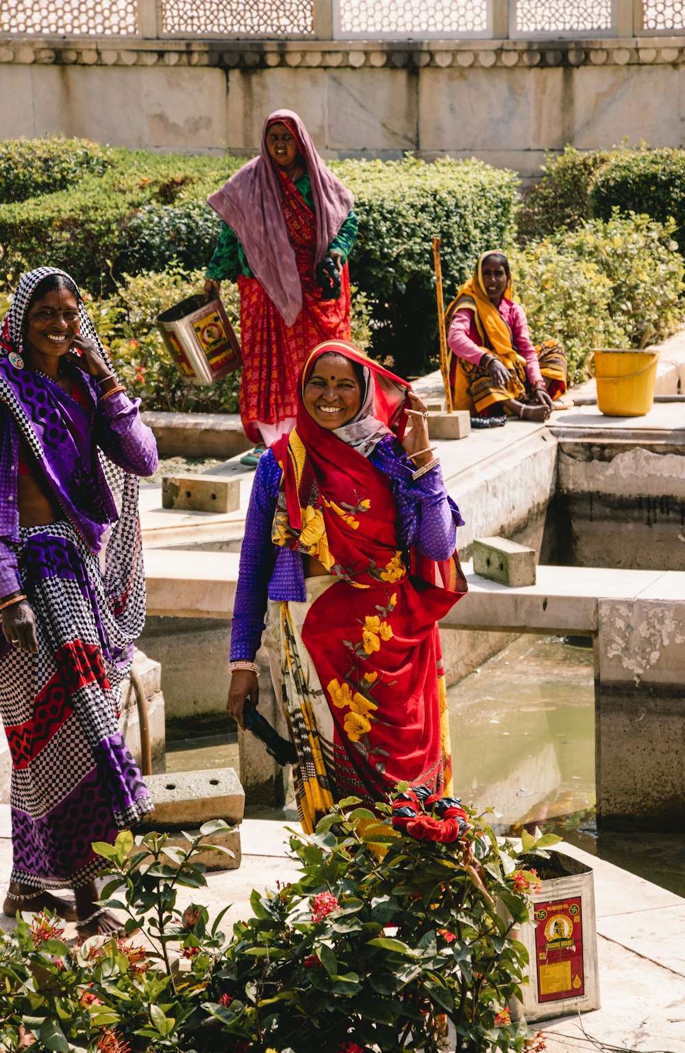 woman in purple and red sari standing beside woman in purple and white hijab