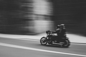grayscale photo of man riding motorcycle