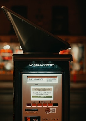 A parking pay station with a sign indicating that no cash is accepted. The screen displays a message stating that the pay station is currently not in operation and timed parking is in effect until October 30, 2020. Various buttons and informational markings are visible on the pay station.