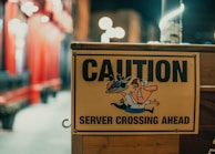 A yellow caution sign warns of a server crossing ahead, featuring a cartoon character of a person balancing a tray with a drink.