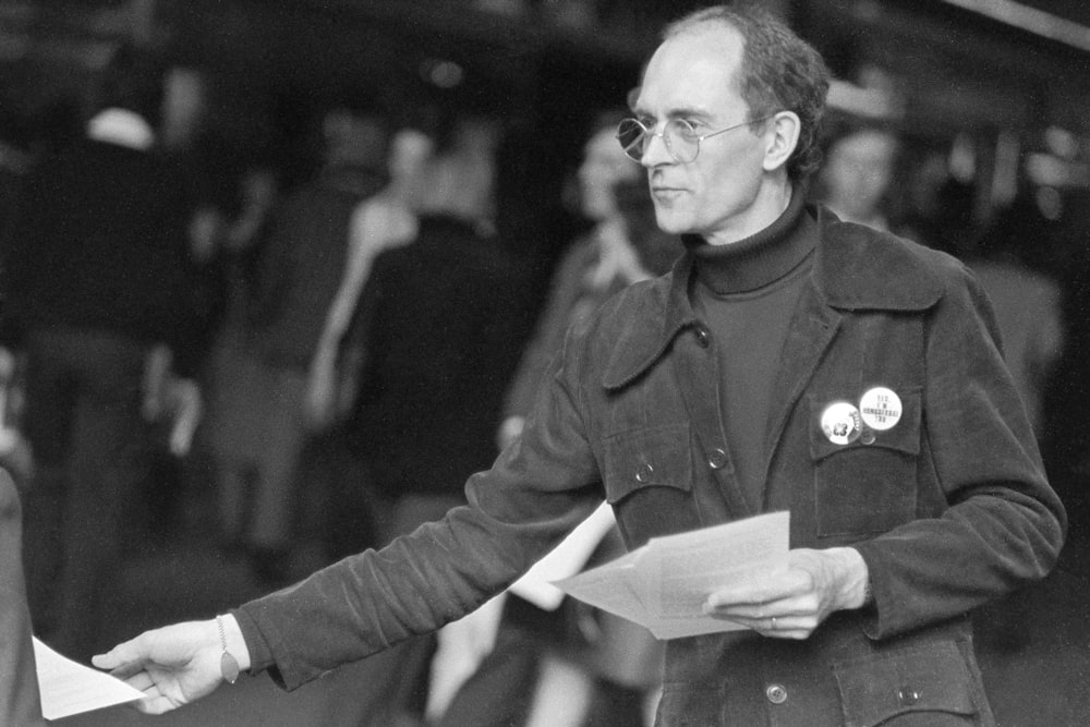 man in black jacket holding white printer paper