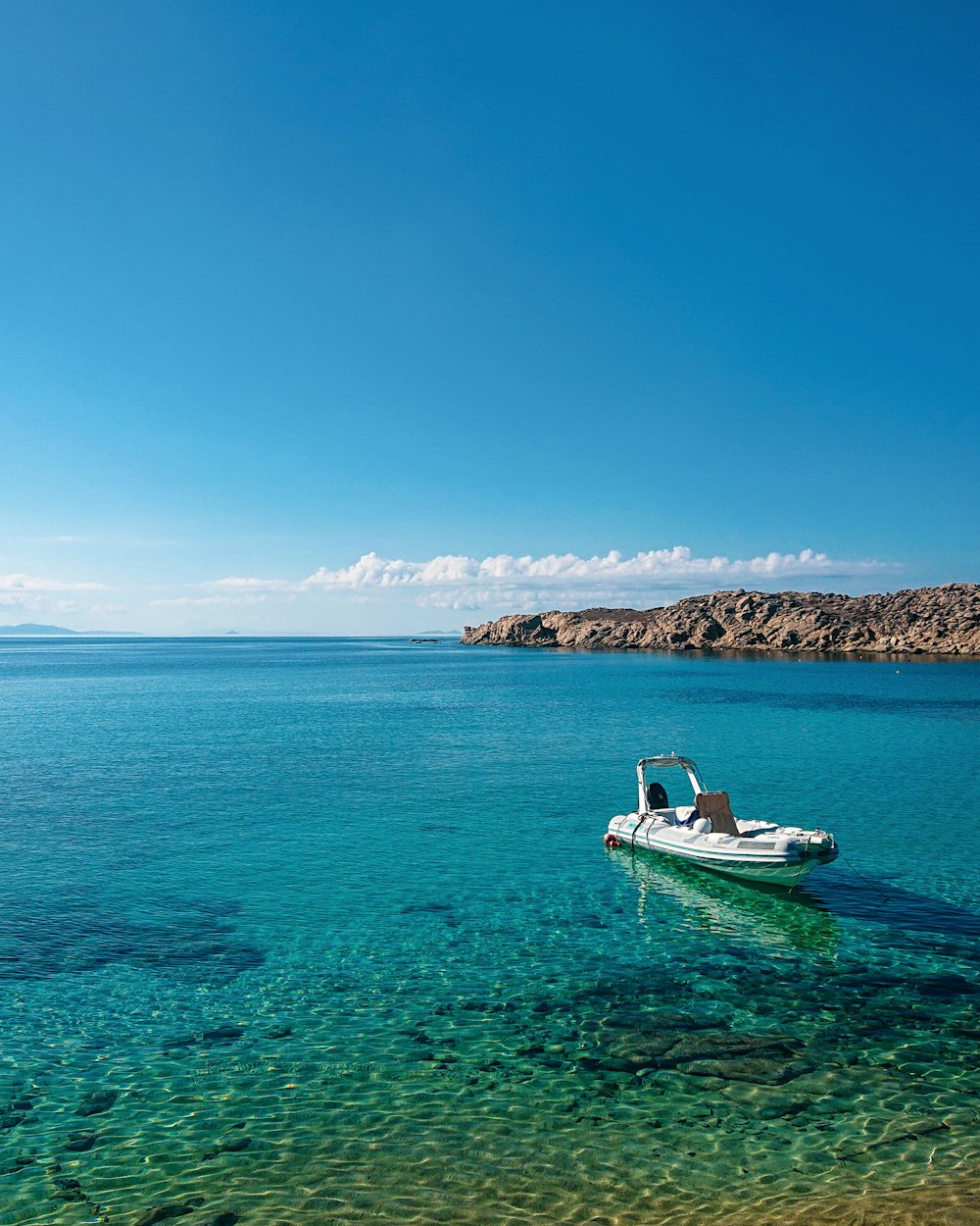 white and blue boat on sea under blue sky during daytime