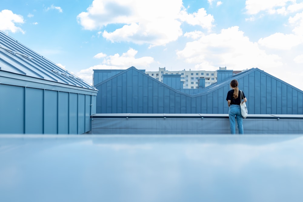 woman in black jacket and blue denim jeans standing on white floor