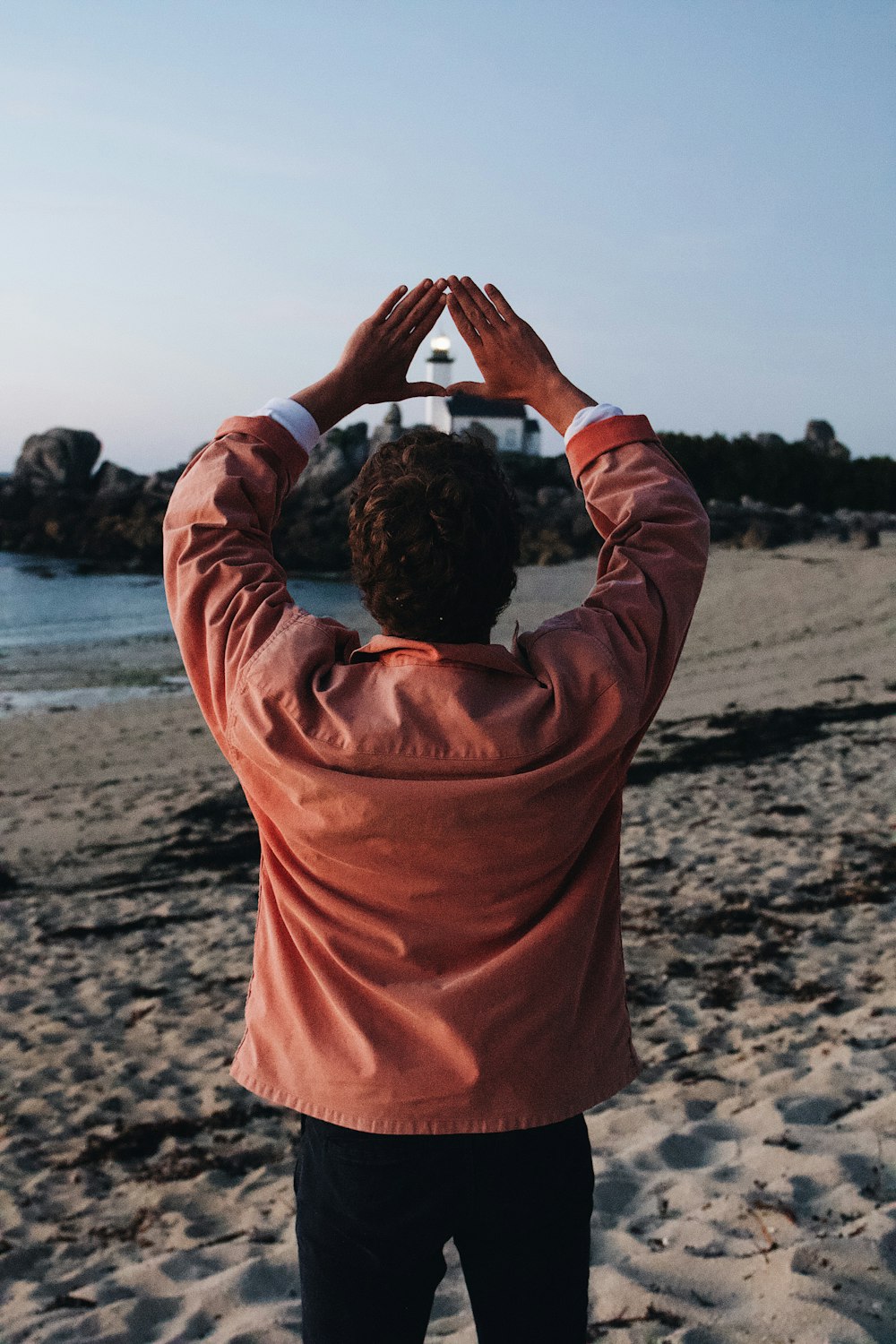 man in orange hoodie covering his face by his hands