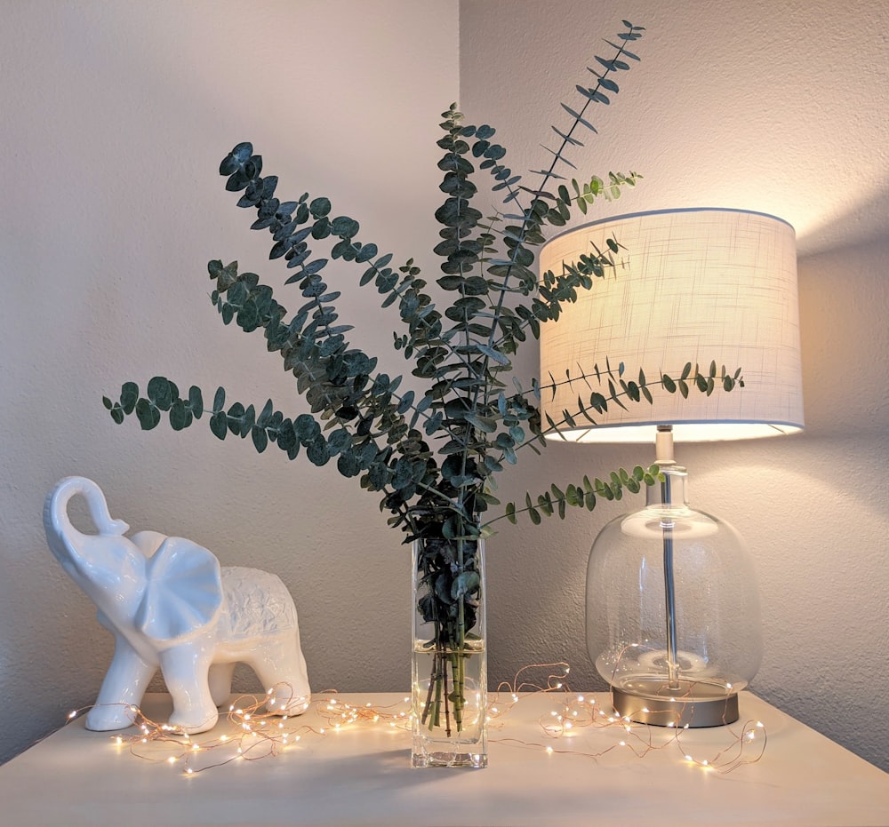 white ceramic swan figurine beside clear glass vase with green plant