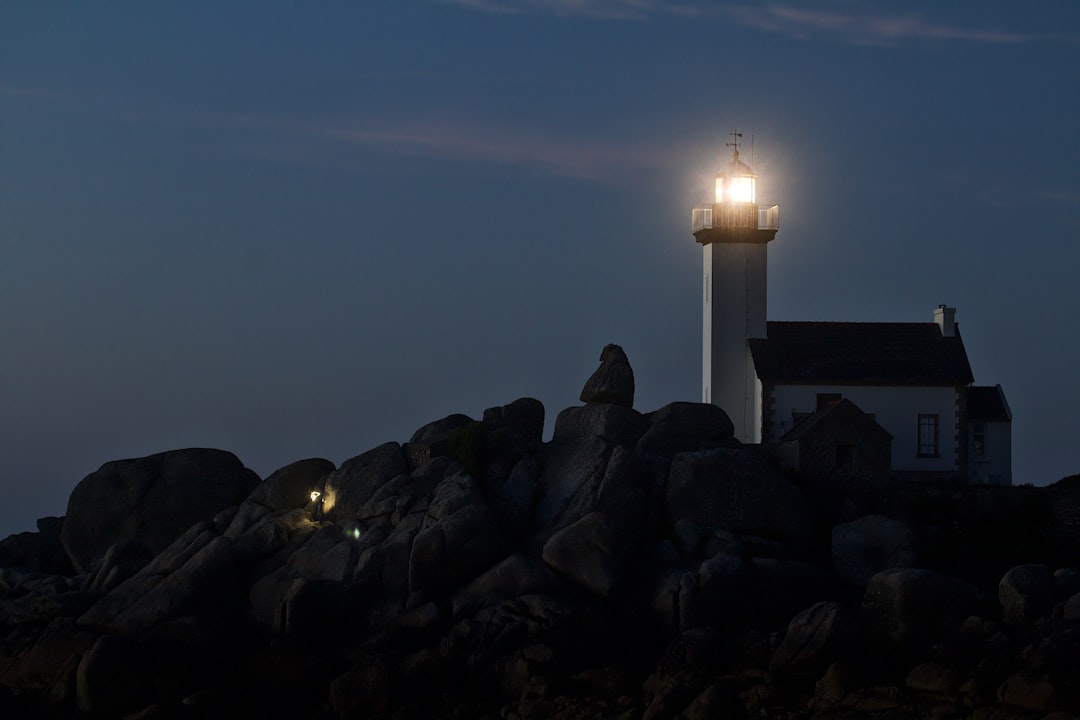 white light tower on rocky shore during night time