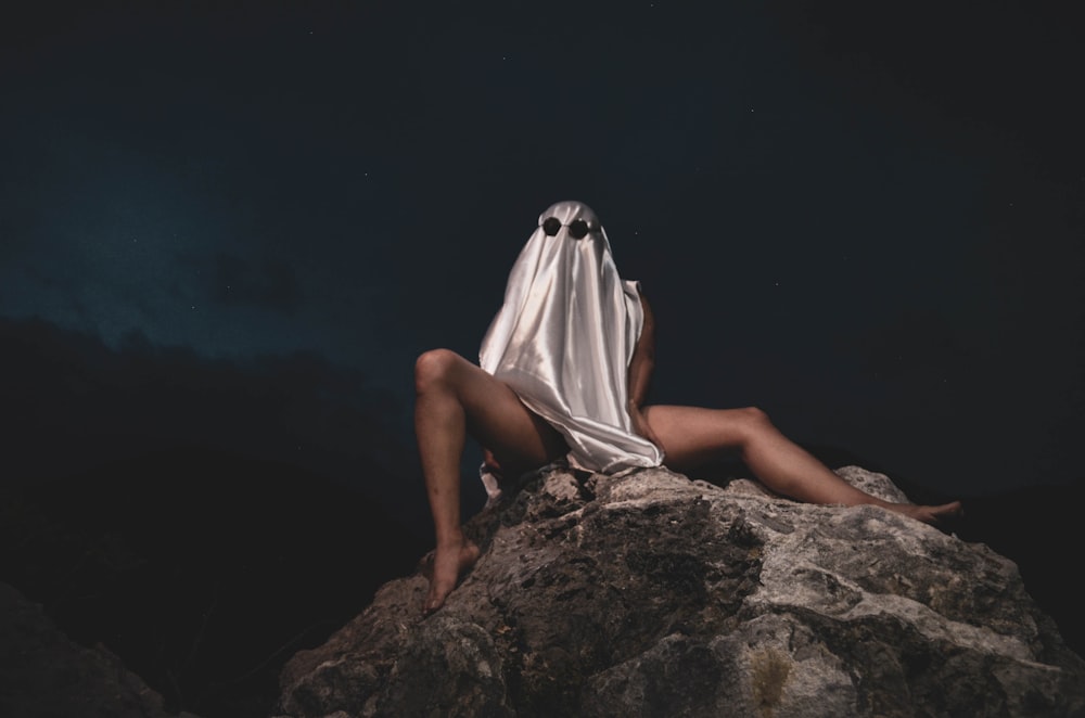 woman in white hijab sitting on brown rock