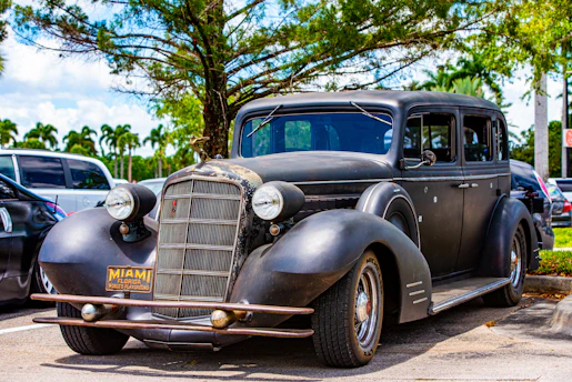 A friendly RapidTrust Auto team member handing cash to a satisfied customer beside a freshly towed junk car in sunny Miami Beach.