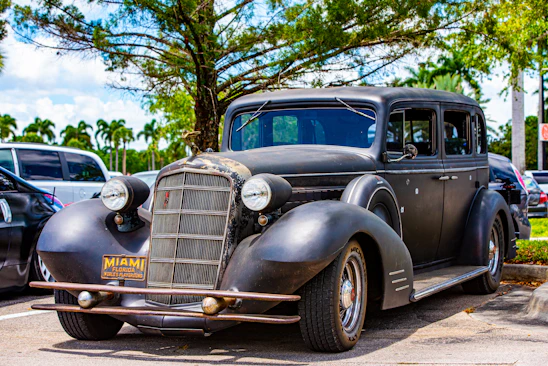 A friendly RapidTrust Auto team member handing cash to a satisfied customer next to a recently towed junk car in Miami Beach.