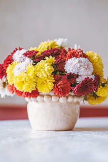 A charming arrangement of seasonal blooms in a hand-painted ceramic pot, bringing warmth to any room.