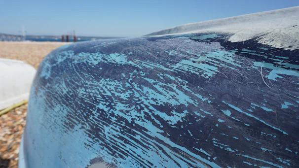 Close-up of a ship hull being coated with marine paint by a technician.