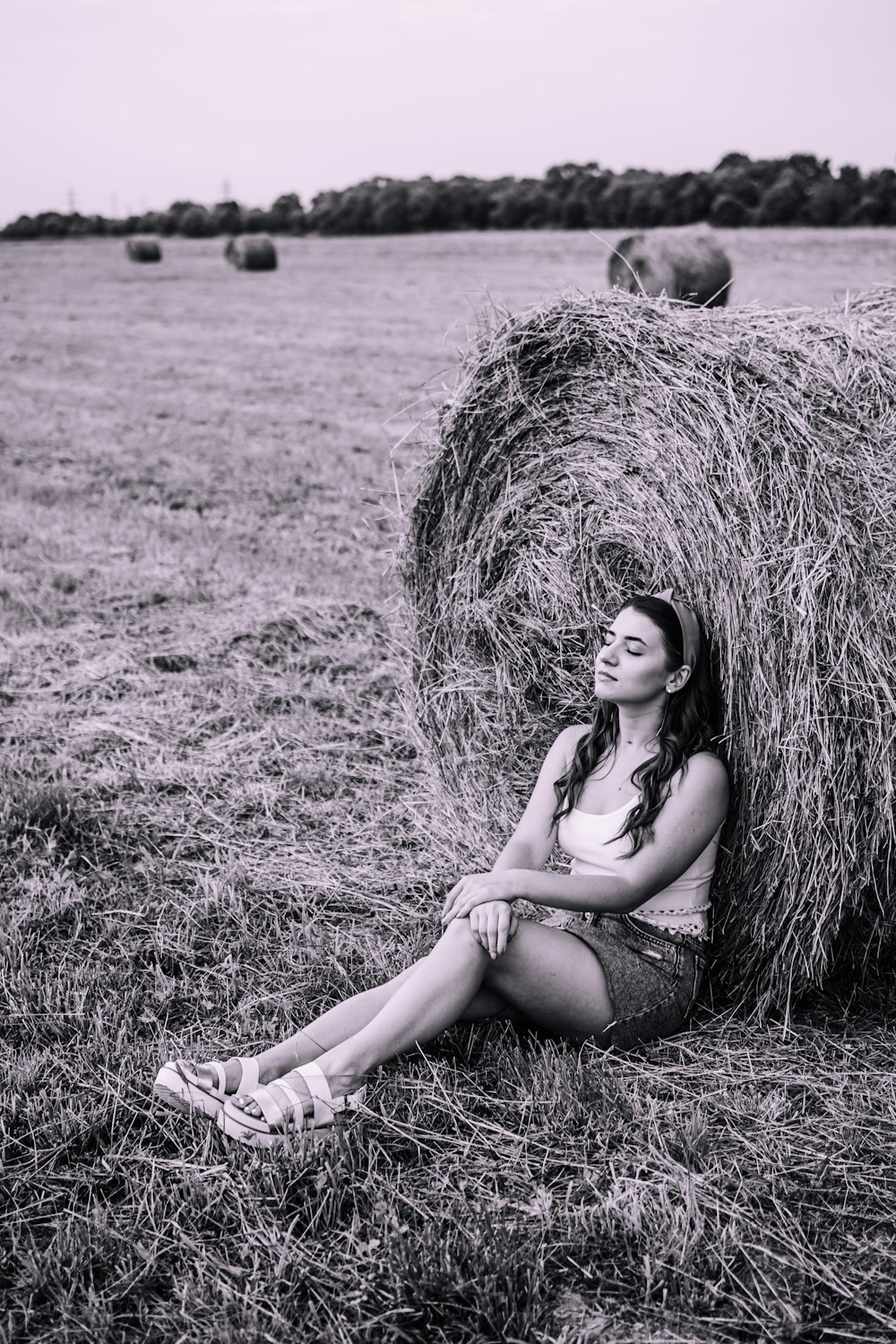 woman in black tank top sitting on hay roll