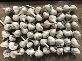 Close-up of assorted garlic bulbs including Himachal and Kashmir varieties arranged on a rustic wooden table.