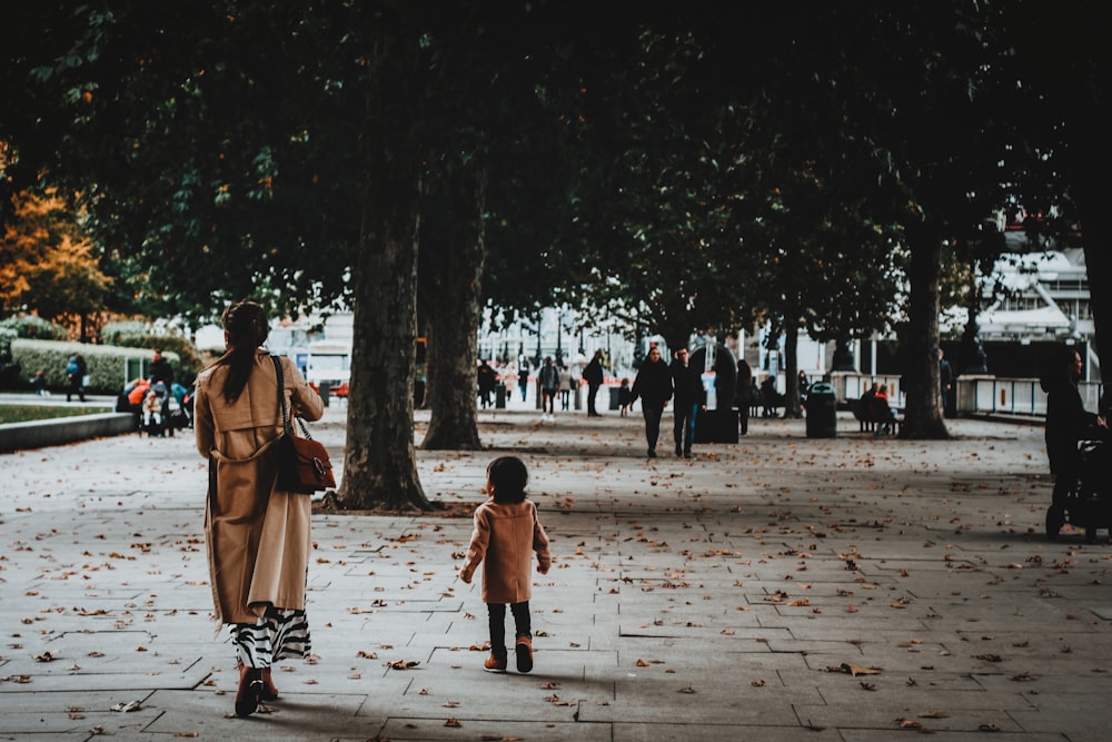 woman in brown coat walking on park during daytime