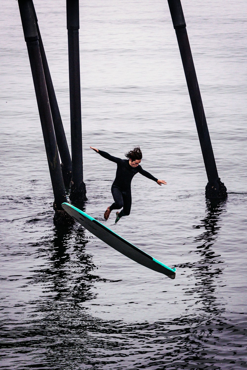 woman in black tank top and black pants sitting on blue surfboard during daytime