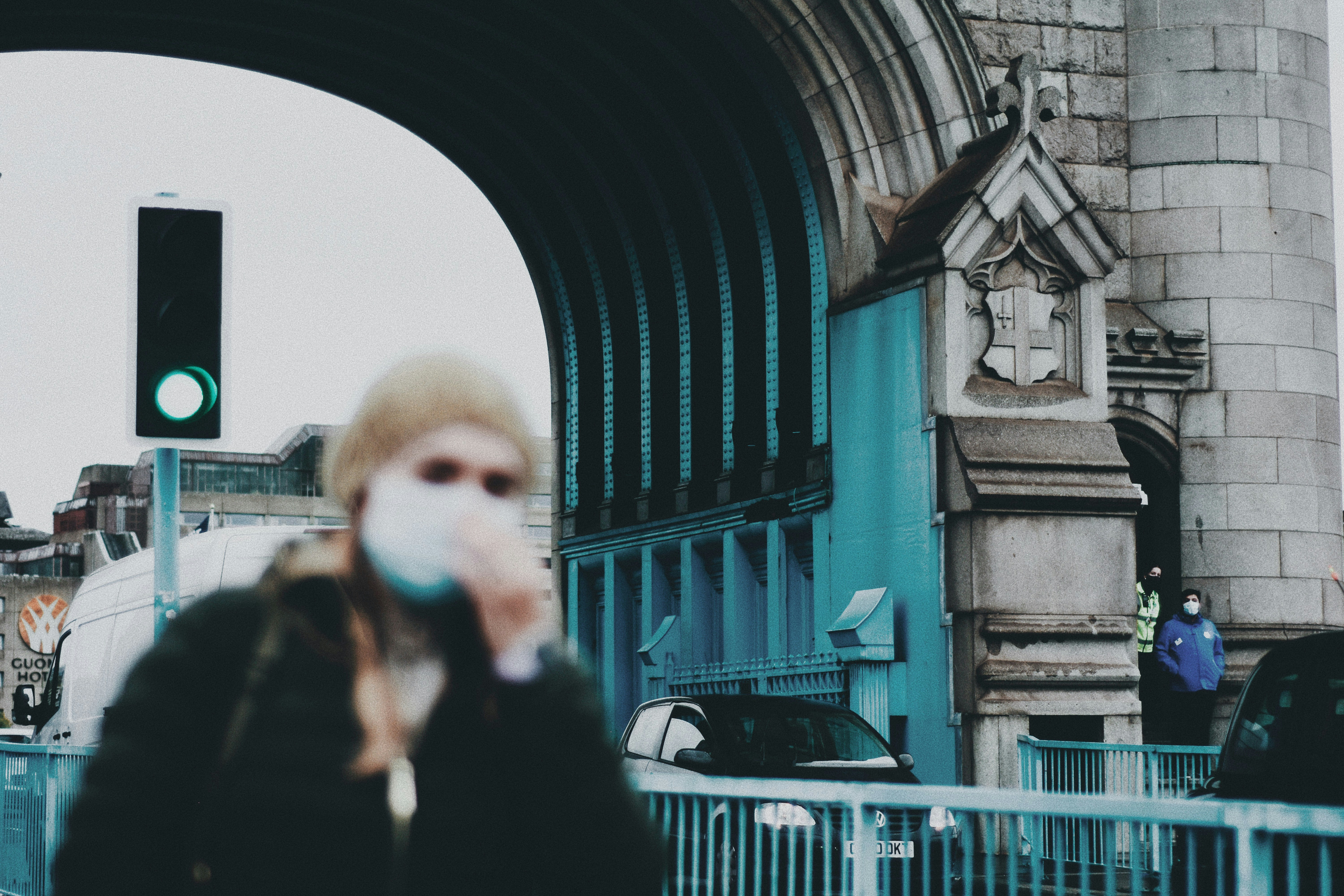 woman in black coat standing near blue metal gate during daytime